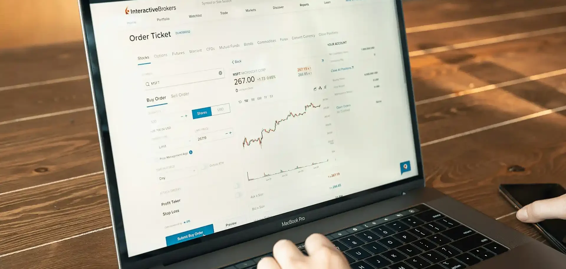 Imagem de uma pessoa usando um notebook e na tela exibe um gráfico de ações em alta.